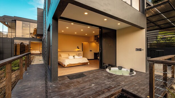 A modern hotel room with a large bed, a private bathroom, and a wooden deck.