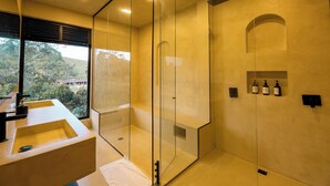 A modern bathroom with a glass-enclosed shower, a large window offering a view of the outdoors, and a minimalist design.