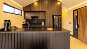 A modern kitchen with a central island, dark wood cabinetry, stainless steel appliances, and a window providing natural light.