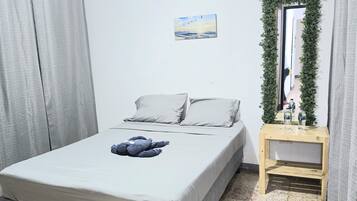 Un dormitorio con una cama, una mesita de noche, un espejo y un equipo de aire acondicionado.