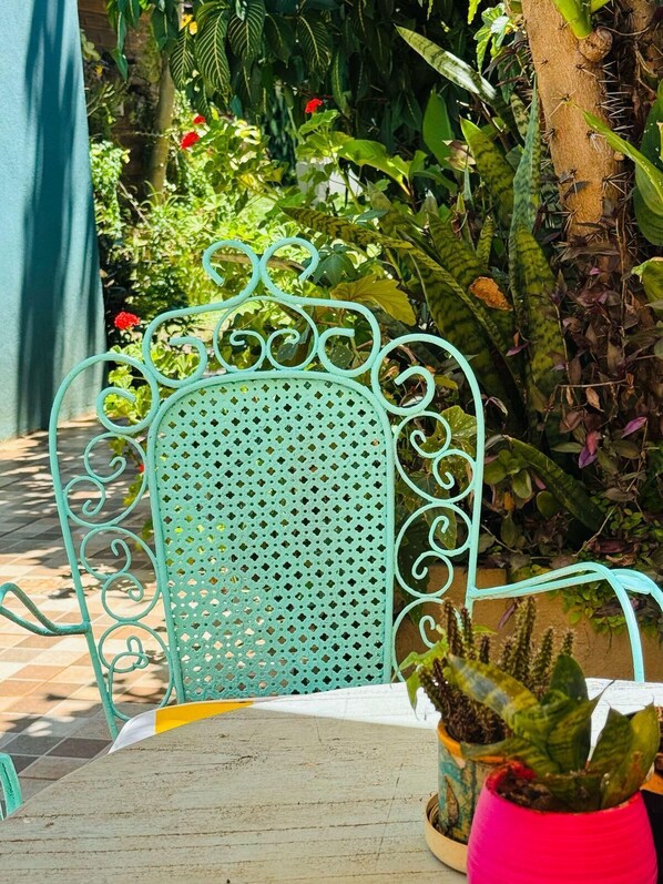 A metal chair with a perforated backrest, a wooden table, and a potted plant with green leaves.