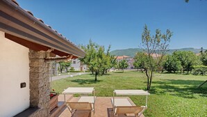Un patio con mobiliario exterior y vistas a un paisaje verde y edificios a lo lejos.