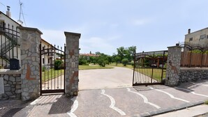 Una entrada protegida con pilares de piedra, un camino de entrada pavimentado y una vista despejada del entorno.