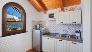 Cocina con armarios blancos, microondas y ventana con vista a follaje.
