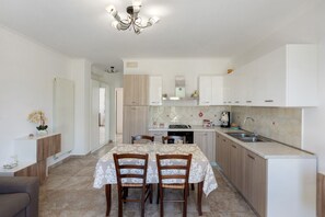 Una cocina moderna con armarios blancos, una mesa de comedor con sillas y una lámpara de araña.