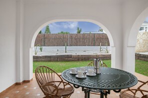 A patio with a round table, chairs, and a coffee pot.