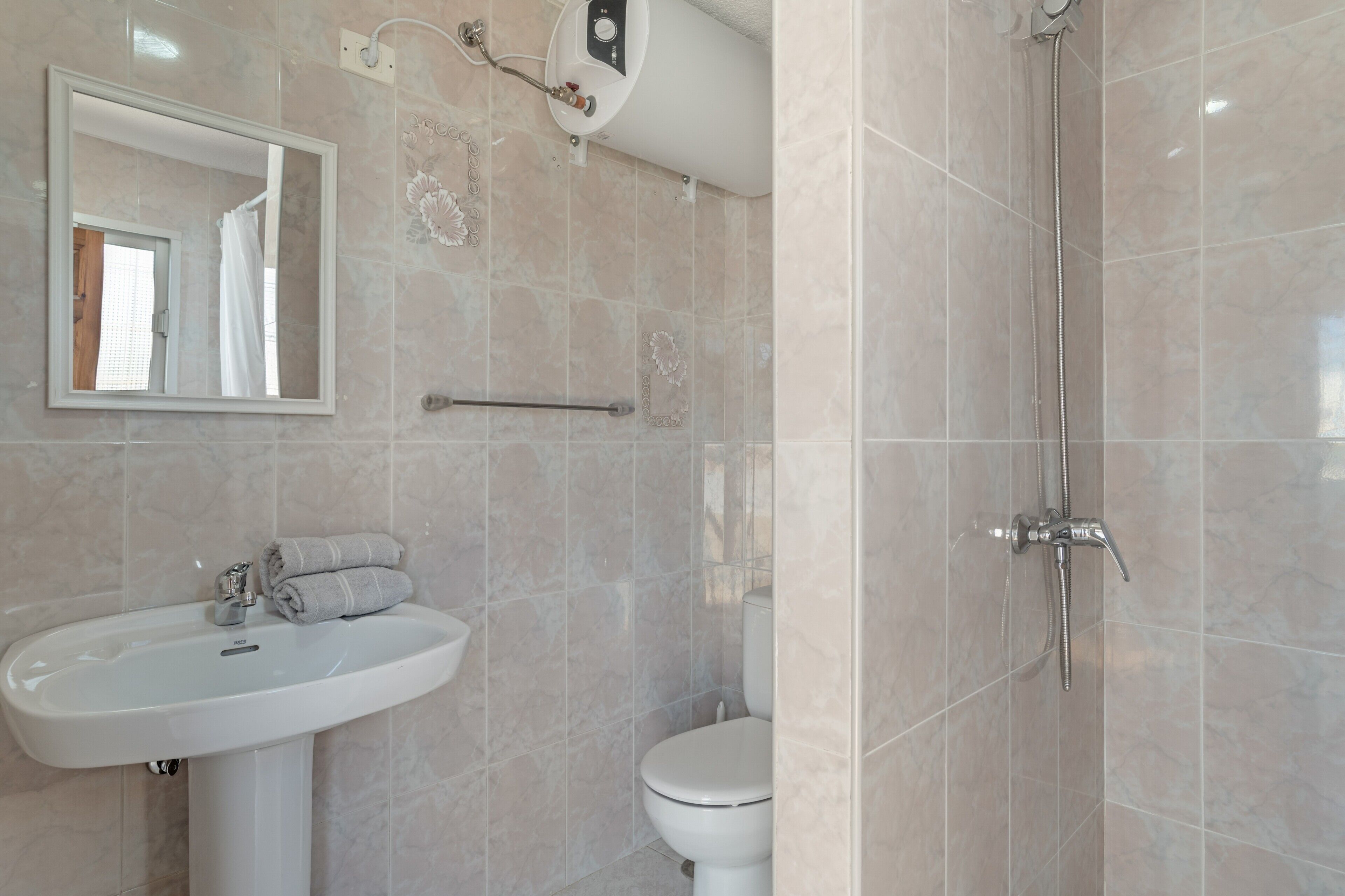 Un baño con lavamanos, espejo, inodoro y ducha.