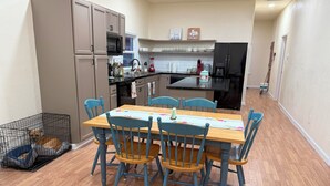 Una cocina compacta con una mesa, sillas y un transportín para mascotas.