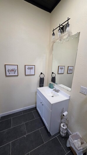 A bathroom with a white vanity, a large mirror, and framed floral artwork on the wall. - 3-bedroom house in charming Waco with WiFi, AC. Start your getaway (Waco)