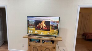 Un televisor sobre un soporte de madera, con un control remoto y algunos libros debajo.