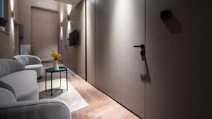 A modern interior with a sofa, a small table with a vase, and a wall-mounted TV.