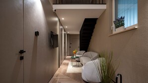A modern interior with a staircase, a sofa, a small table with a vase, and a potted plant.