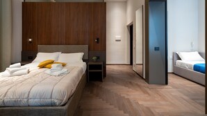 A modern bedroom with a large bed, bedside tables, a mirror, and a separate seating area.