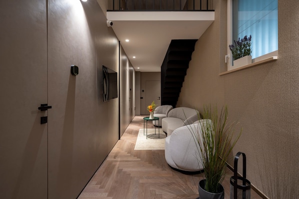 A modern interior with a staircase, a sofa, a small table with a vase, and a potted plant.