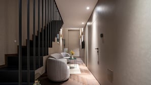 A modern interior with a staircase, a sofa, a small table with a vase, and a flat-screen TV mounted on the wall. - Apartment In A Hotel '4 Season Cognetti Room 3' with Wi-Fi and Air Conditioning (Bari)