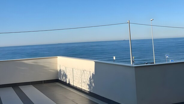 Vista limpida sul mare da un balcone con pavimento piastrellato e ringhiera.