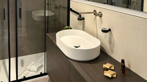 Un bagno moderno con cabina doccia in vetro, lavandino bianco e uno specchio grande.