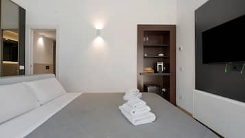 Habitación de hotel moderna con una cama grande, un televisor de pantalla plana montado en la pared, un mueble de almacenamiento empotrado y un espejo en la pared izquierda.