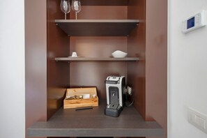 Una piccola cucina attrezzata con una macchina da caffè, una scatola di legno e una tazza sul piano di lavoro.