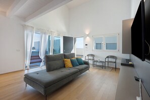 A modern living room with a grey sofa, two chairs, a small table, and a TV mounted on the wall. - 'Luxury Terrazza' Apartment with Sea View, Wi-Fi, and Air Conditioning (Bari)