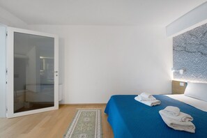 A hotel room with a bed, a bathroom, and a door leading to another room. - 'Luxury Terrazza' Apartment with Sea View, Wi-Fi, and Air Conditioning (Bari)