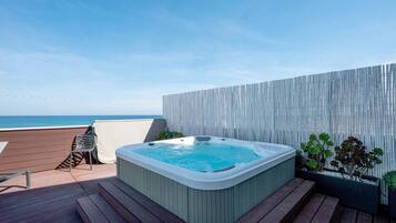 A hot tub on a deck with a view of the ocean.