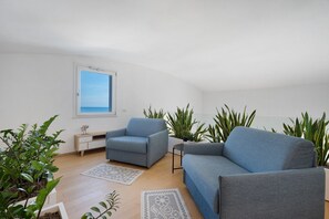 A modern living room with a sofa, armchair, and potted plants. - 'Luxury Terrazza' Apartment with Sea View, Wi-Fi, and Air Conditioning (Bari)