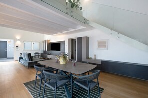 A modern interior with a dining area, a sofa, a TV, and a staircase. - 'Luxury Terrazza' Apartment with Sea View, Wi-Fi, and Air Conditioning (Bari)