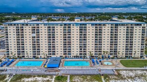 Un hotel grande con varios pisos, una piscina en la azotea y una zona de playa con tumbonas.