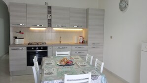 Una cocina moderna con una mesa de comedor, sillas y un reloj en la pared.