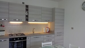 Una cocina moderna con estufa a gas, pileta y alacenas de madera.