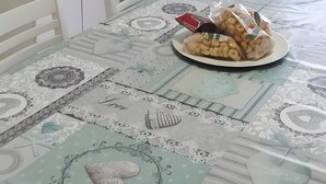 Una mesa de comedor con mantel estampado, un plato de aperitivos y un televisor montado en la pared.
