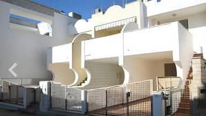Un edificio moderno con entrada porticada, una escalera y techo plano.