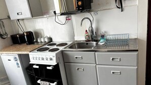 A compact kitchen with a stove, sink, and a small refrigerator.
