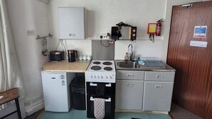 A compact kitchenette with a stove, sink, and small refrigerator.