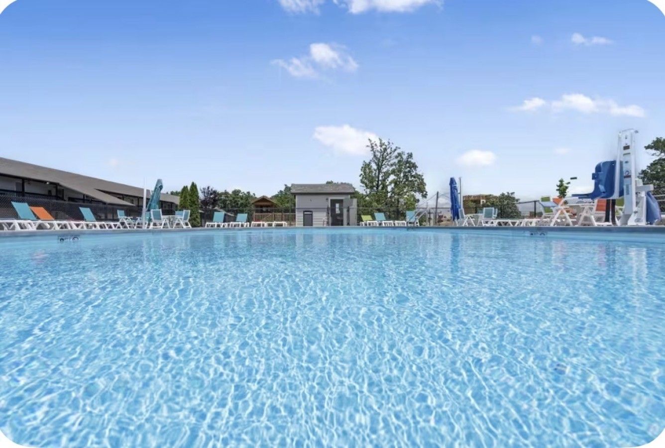 Ein Schwimmbecken mit klarem Wasser, umgeben von Liegestühlen und einem Gebäude im Hintergrund.
