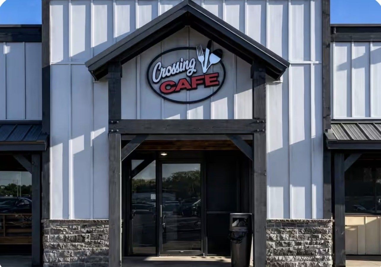 Un edificio con un cartel que dice 'Crossing Cafe' sobre la entrada.