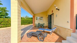 A covered patio with a table and chairs, a ping pong table, and a door. - Holiday Home 'Villetta Il Boschetto' with Shared Pool, Private Garden and Air Conditioning (Morciano di Leuca)