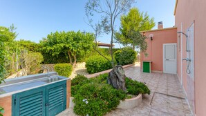 A patio with a sink, a green door, and a tree. - Holiday Home 'Villetta Il Boschetto' with Shared Pool, Private Garden and Air Conditioning (Morciano di Leuca)