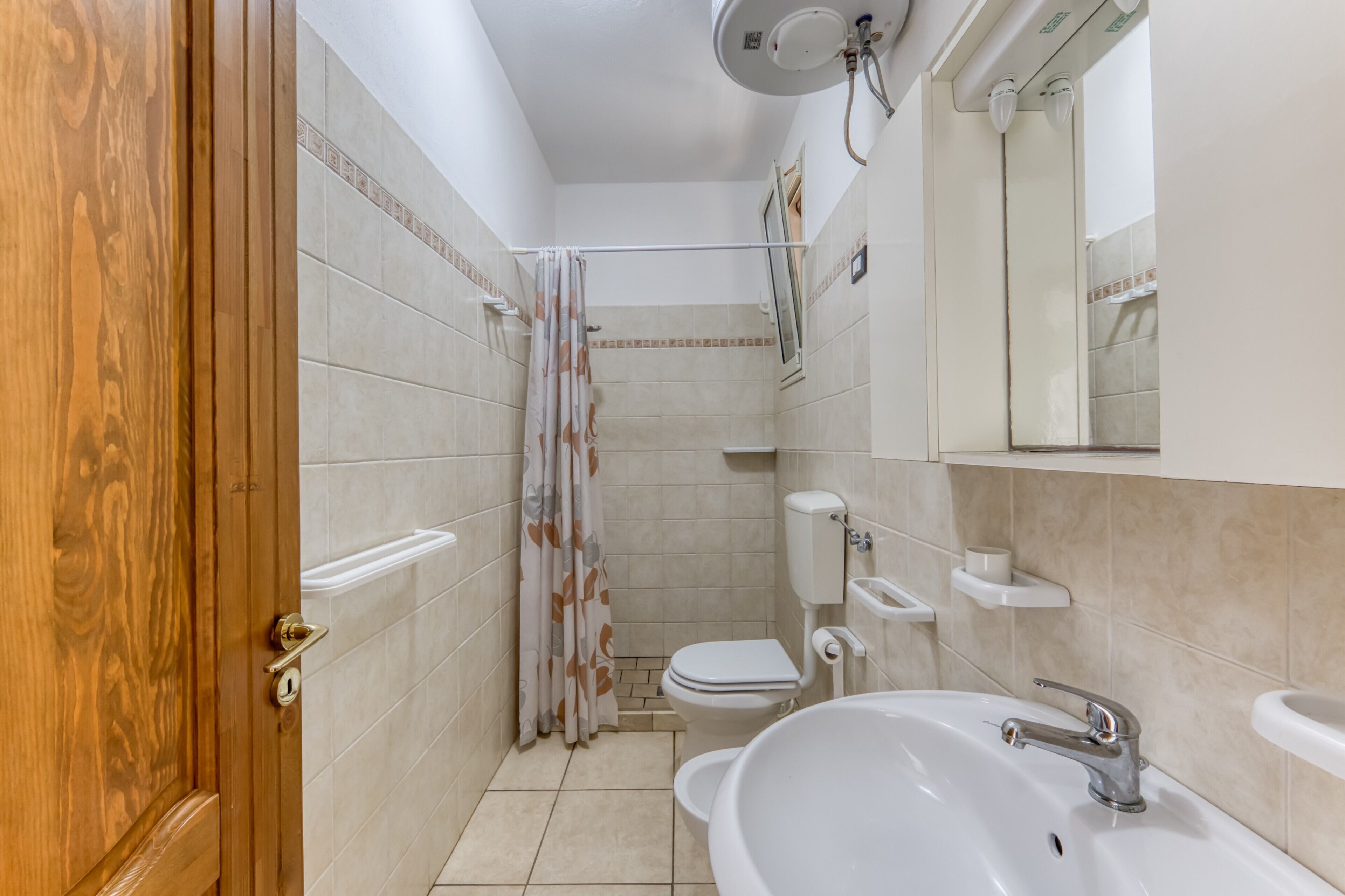 Une salle de bain comprenant des toilettes, un lavabo, une douche et une porte en bois.