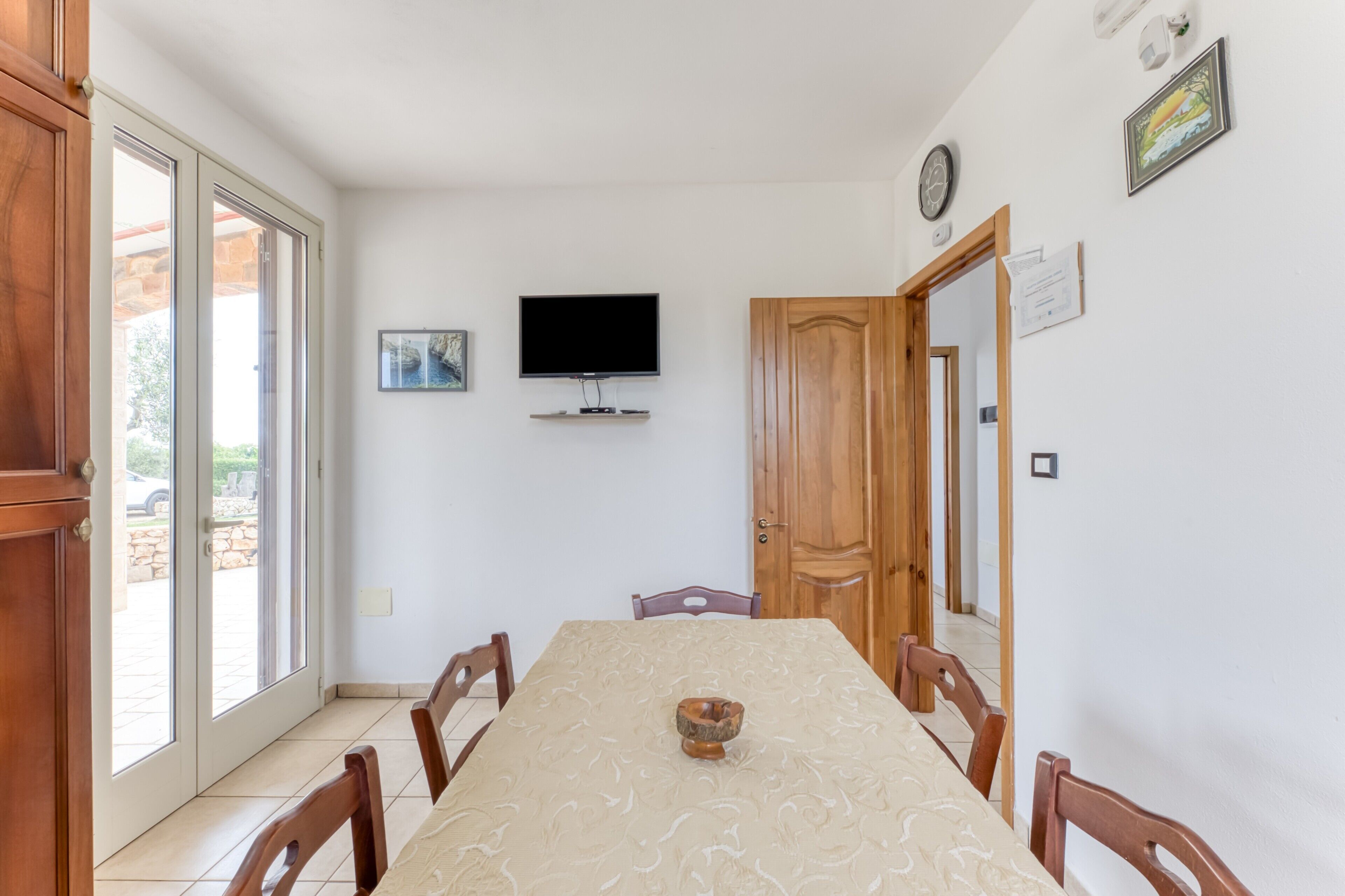 A dining area with a table, chairs, a television, and a door.