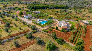 Una propiedad rural con piscina, edificios de piedra y campos en terrazas.