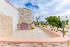 A stone building with a curved wall, a paved patio, and a lamp post.