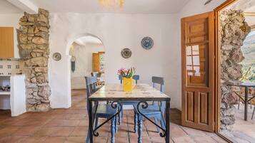 A dining area with a stone wall, a wooden door, and a view through an archway.