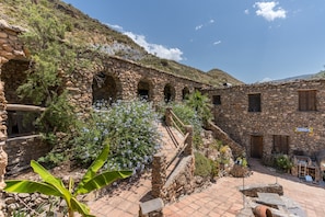 A stone building with arched doorways, a staircase, and a sign reading 'PERNO 45'.