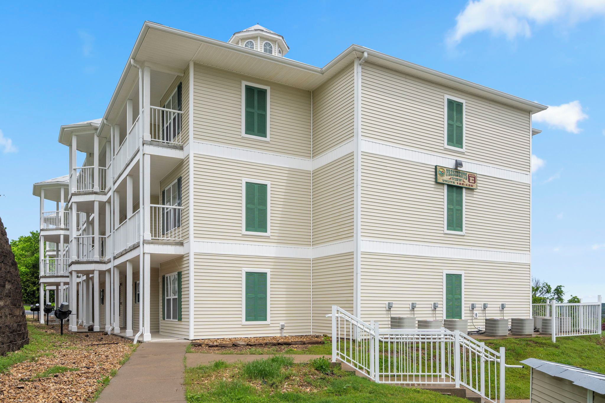 A multi-story building with balconies, a covered walkway, and a fenced outdoor area.