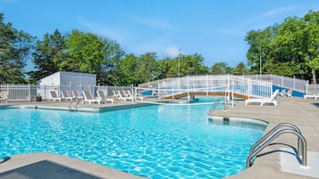 A swimming pool with multiple lanes, a white fence, and lounge chairs.