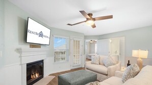 Ein Wohnzimmer mit Kamin, Deckenventilator und Wandfernseher.