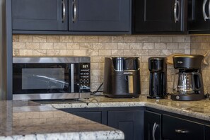 Une cuisine équipée d’un four à micro-ondes, d’une machine à café et d’une cafetière.