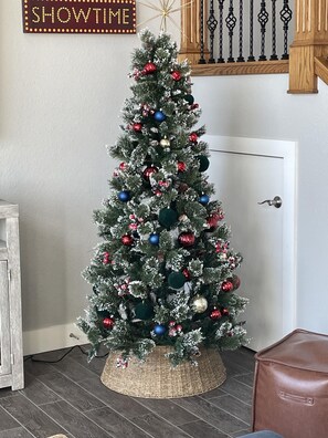 A Christmas tree with ornaments, placed in a corner with a door and a sign above it.